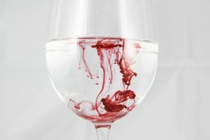 een glas water met rode vloeistof die bloed symboliseert
