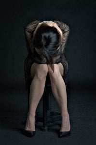 depressieve vrouw zit op stoel met hoofd voorovergebogen