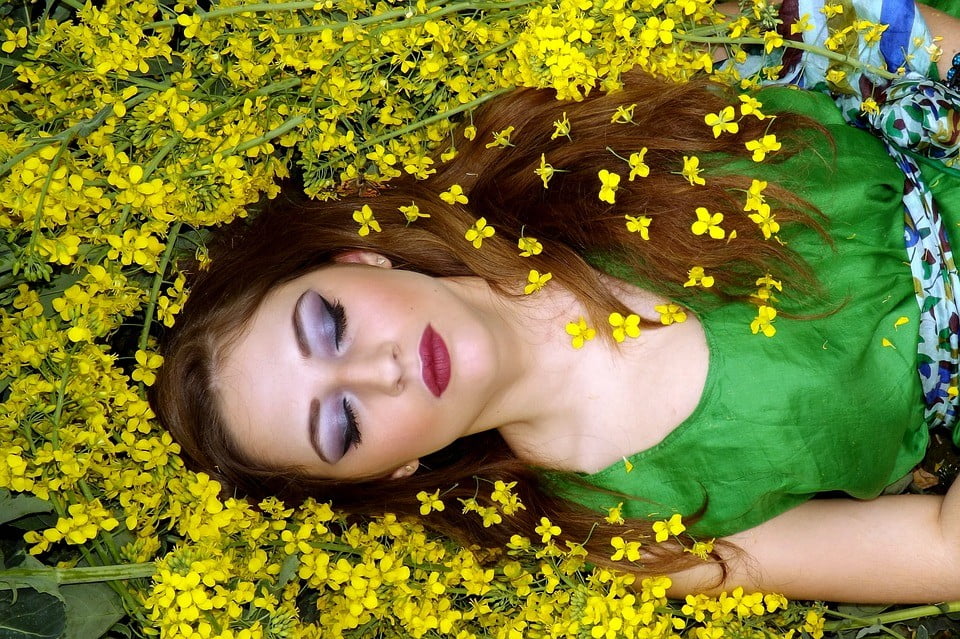 vrouw ligt op de grond tussen bloemen te dromen