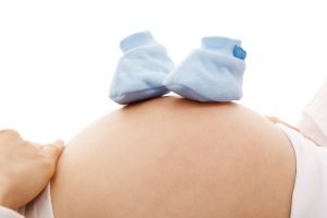 zwangere buik met blauwe schoentjes erop