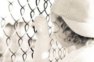 boy stands behind fence